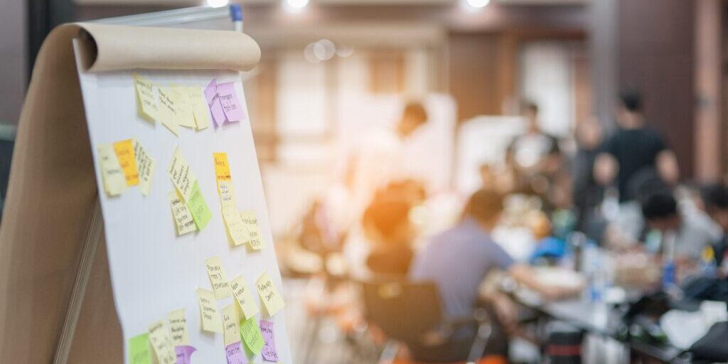 Scrum-Board im Vordergrund eines Agile Transformation-Coaching