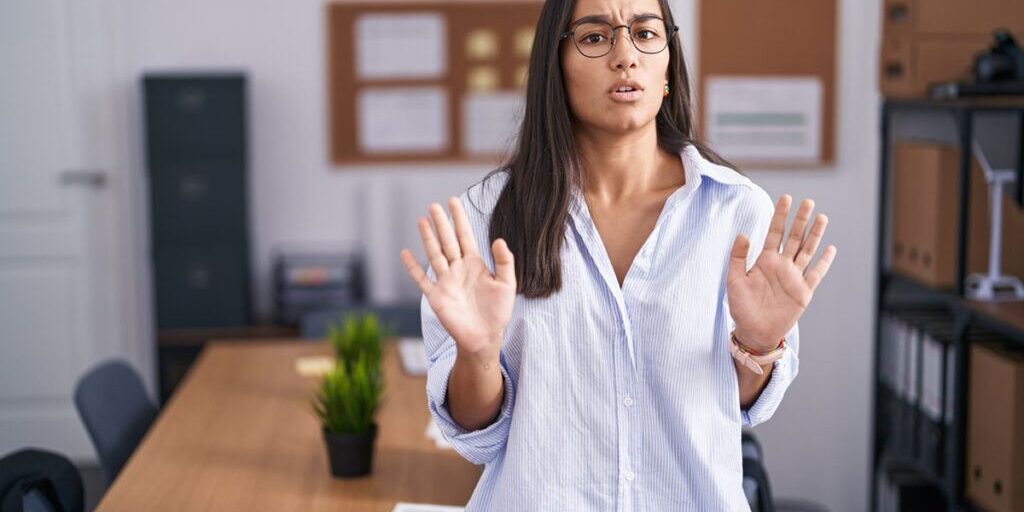 Nein sagen lernen: junge Frau hebt abwehrend die Hände