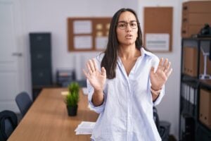 Nein sagen lernen: junge Frau hebt abwehrend die Hände