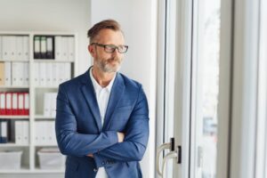 Traumjob finden: ein Mann schaut nachdenklich aber optimistisch aus dem Fenster